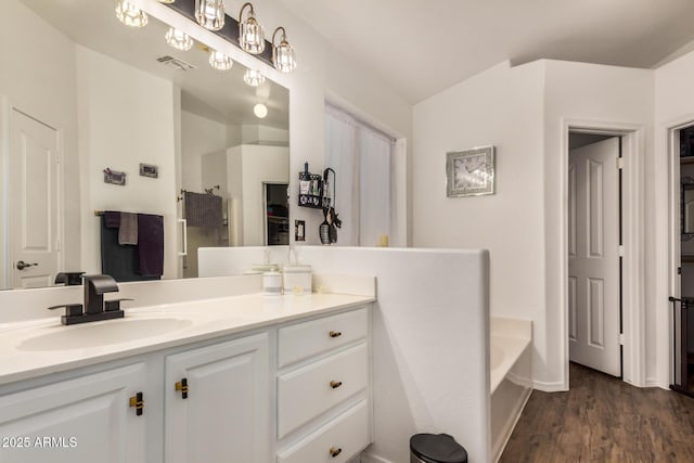 full bathroom with visible vents, vanity, wood finished floors, baseboards, and a bath