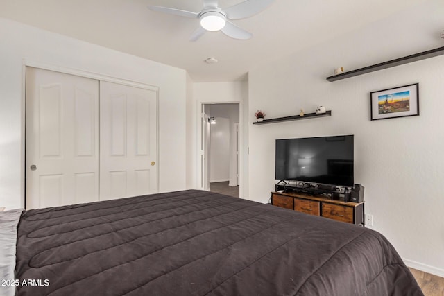 bedroom with a ceiling fan, baseboards, wood finished floors, and a closet