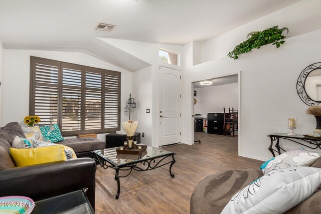 living area with visible vents, baseboards, lofted ceiling, and wood finished floors