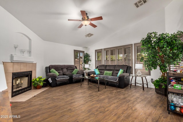 living area featuring a tiled fireplace, a ceiling fan, light wood finished floors, and visible vents