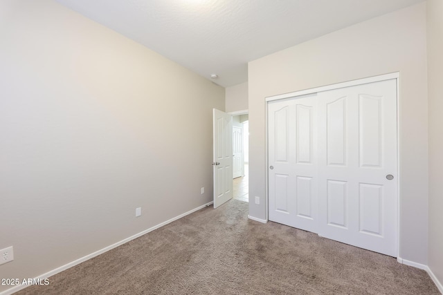 unfurnished bedroom with light carpet and a closet