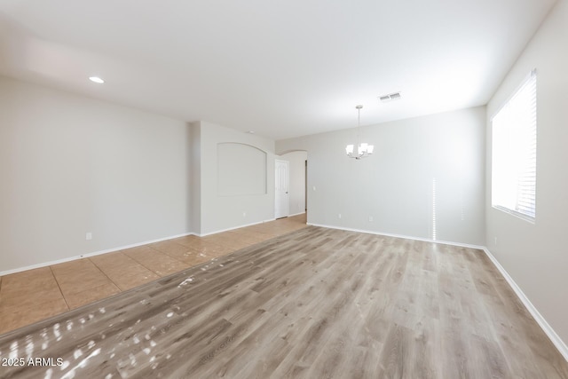 empty room featuring light wood-type flooring and a chandelier