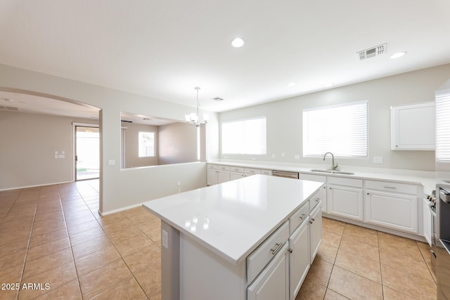 kitchen with hanging light fixtures, white cabinets, sink, and a center island