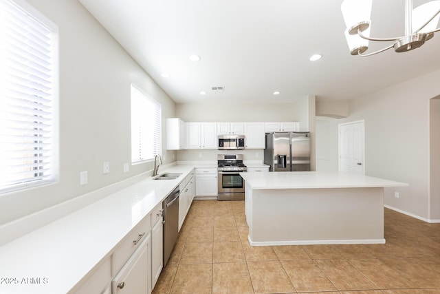 kitchen featuring white cabinets, appliances with stainless steel finishes, a kitchen island, sink, and light tile patterned flooring