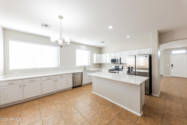 kitchen featuring decorative light fixtures, a center island, sink, appliances with stainless steel finishes, and white cabinets