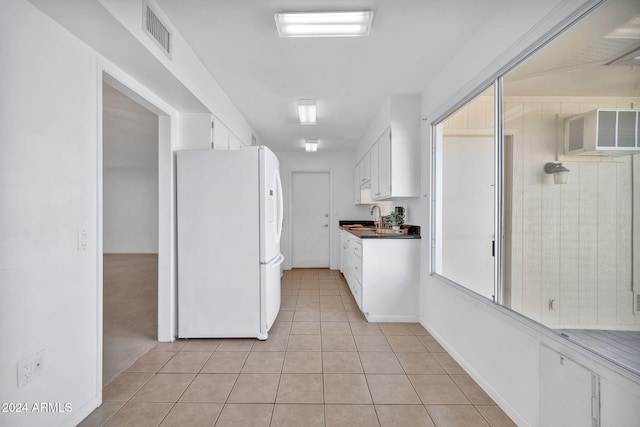 kitchen with a wall mounted AC, sink, light tile patterned floors, white cabinets, and white fridge