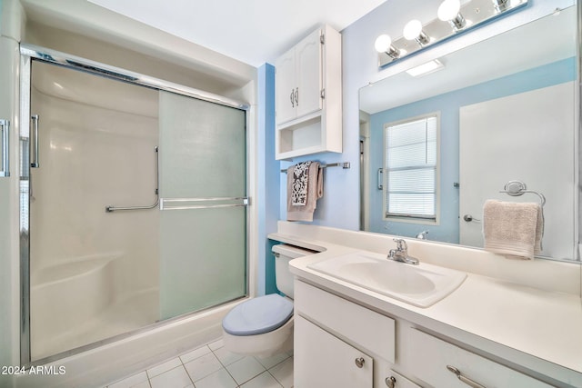 bathroom featuring tile patterned flooring, vanity, toilet, and a shower with shower door