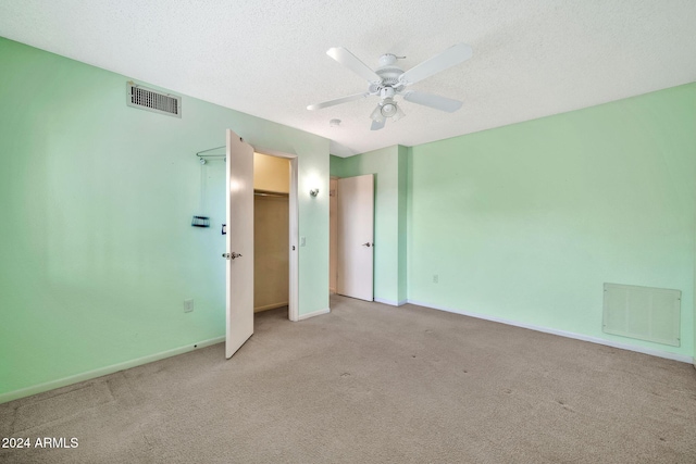 unfurnished bedroom featuring ceiling fan, light colored carpet, and a textured ceiling