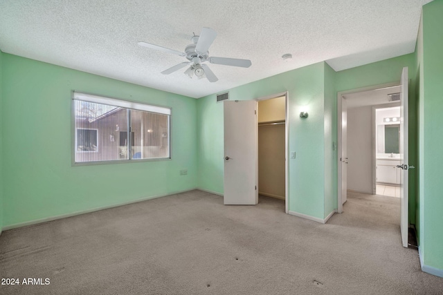 unfurnished bedroom featuring a textured ceiling, ceiling fan, light carpet, and a closet