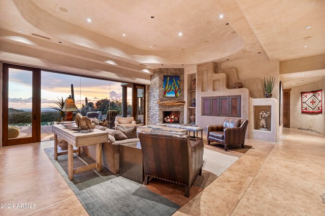 tiled living room featuring built in features, a raised ceiling, and a fireplace