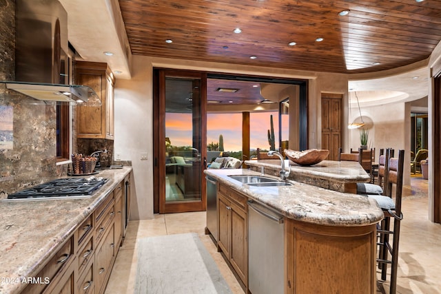 kitchen featuring wall chimney range hood, backsplash, a kitchen bar, light tile floors, and sink