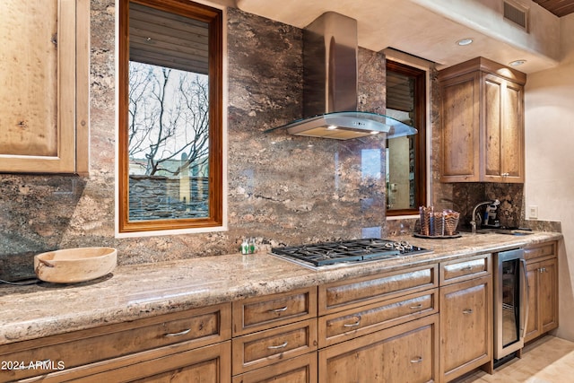 kitchen with stainless steel gas cooktop, tasteful backsplash, wall chimney range hood, wine cooler, and sink