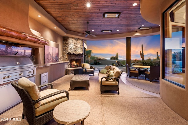 patio terrace at dusk featuring an outdoor living space with a fireplace, ceiling fan, an outdoor kitchen, and a grill