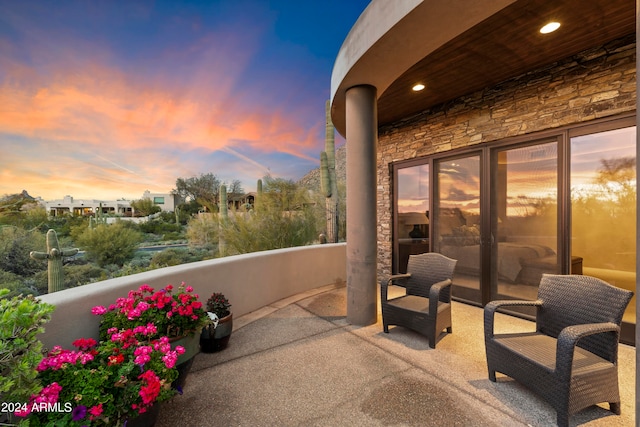 patio terrace at dusk featuring a balcony