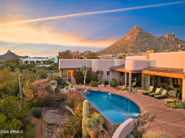 pool at dusk with a mountain view and a patio