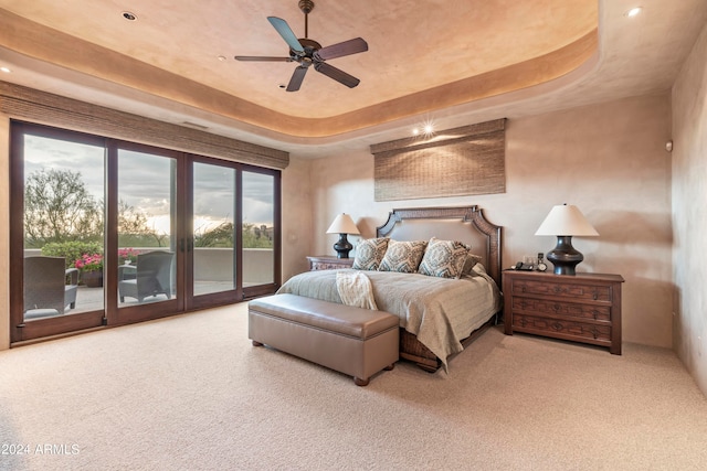 carpeted bedroom featuring a tray ceiling, ceiling fan, and access to outside