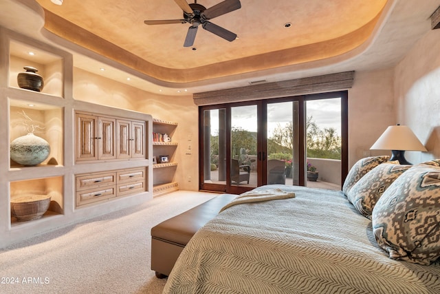 carpeted bedroom with ceiling fan, access to exterior, and a tray ceiling