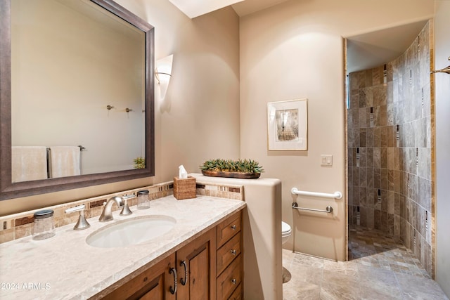 bathroom with vanity, tile flooring, a tile shower, and toilet