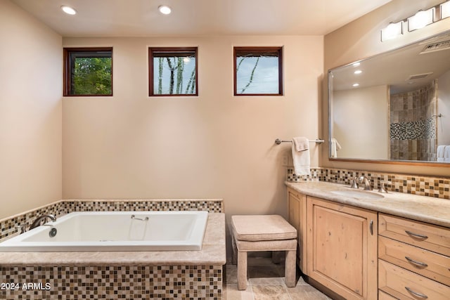 bathroom featuring tile floors, tasteful backsplash, tiled bath, and vanity