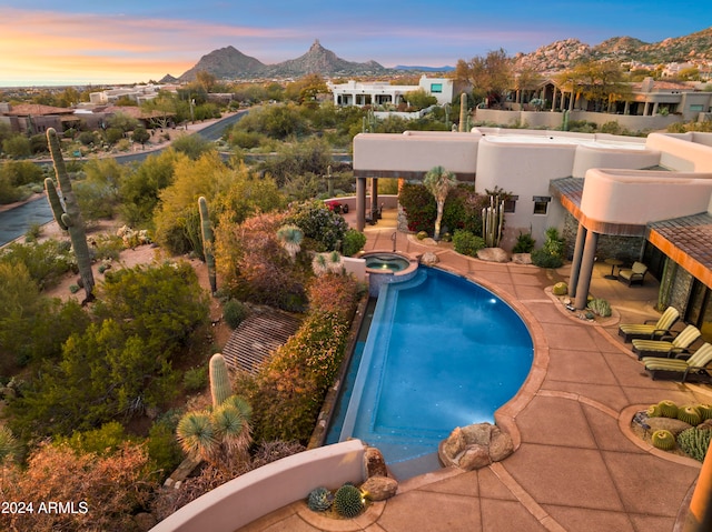 pool at dusk featuring a mountain view and a patio area