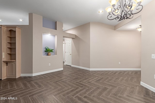 spare room with a chandelier and dark parquet flooring