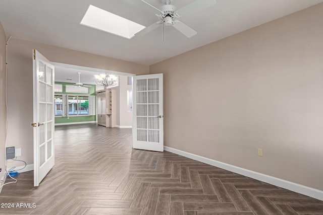 unfurnished room with ceiling fan with notable chandelier, dark parquet flooring, a skylight, and french doors