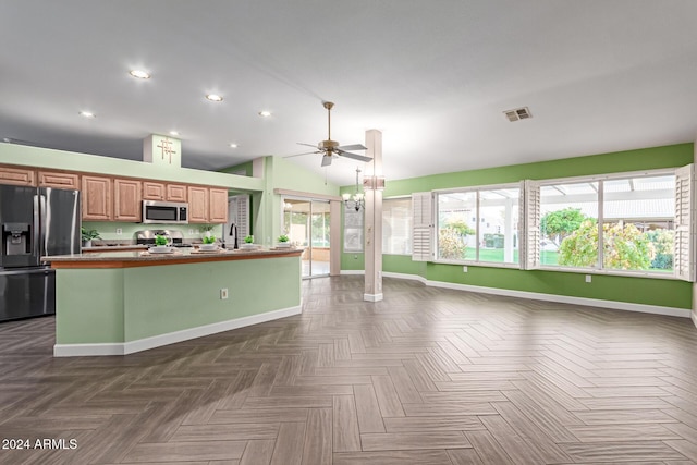 kitchen with dark parquet flooring, stainless steel appliances, sink, lofted ceiling, and an island with sink