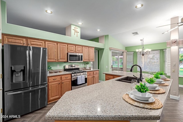 kitchen with vaulted ceiling, sink, appliances with stainless steel finishes, and an island with sink