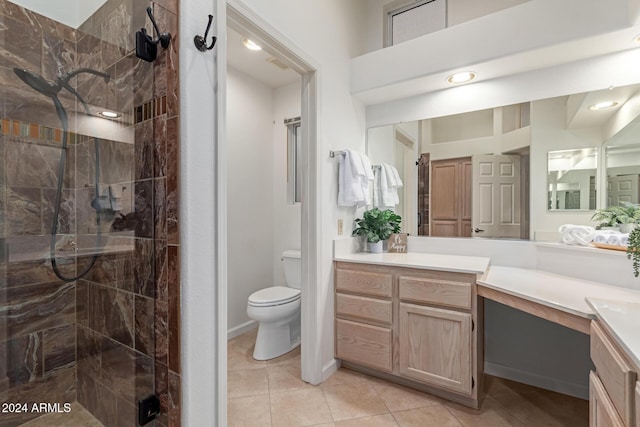 bathroom with tile patterned flooring, vanity, toilet, and tiled shower