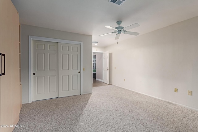 unfurnished bedroom featuring ceiling fan, a closet, and light colored carpet