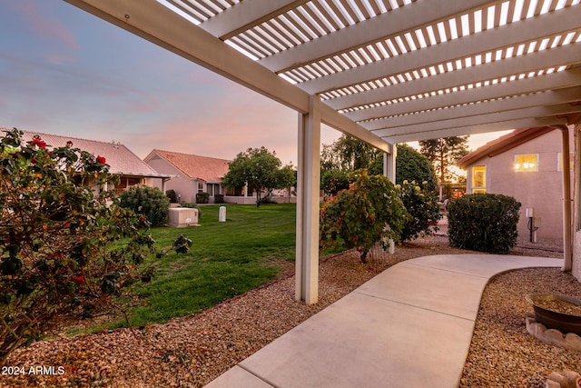 patio terrace at dusk with a pergola and a lawn