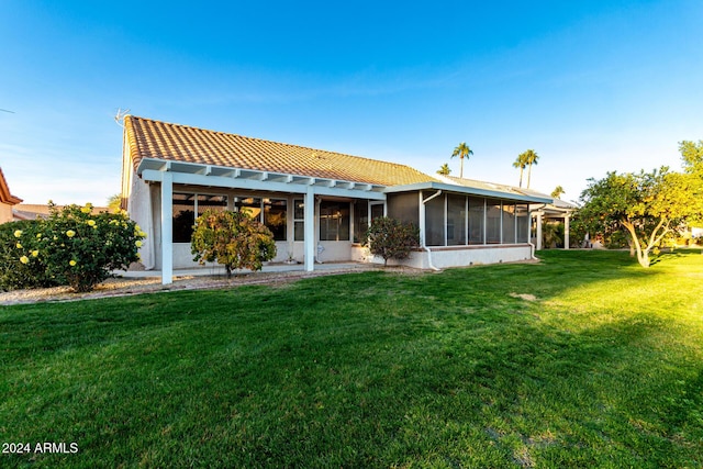 back of property featuring a sunroom and a yard