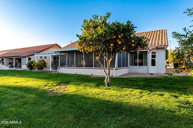 rear view of house featuring a lawn and a sunroom