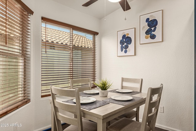 dining space featuring baseboards, a ceiling fan, and a textured wall