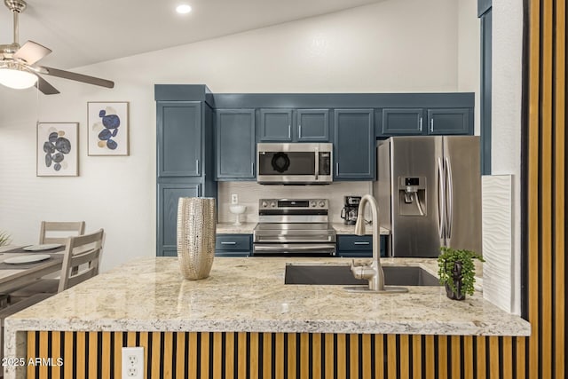 kitchen featuring light stone counters, ceiling fan, a sink, and stainless steel appliances