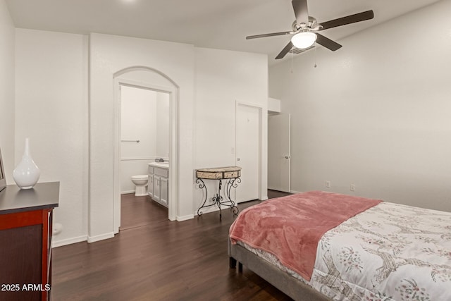 bedroom featuring dark wood-type flooring, baseboards, vaulted ceiling, and connected bathroom