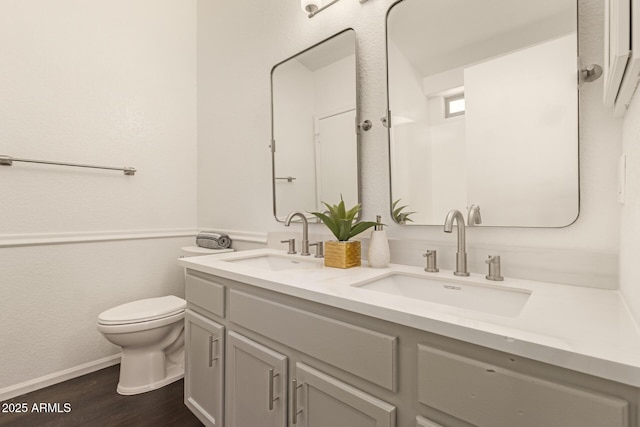 full bathroom featuring double vanity, a sink, toilet, and wood finished floors