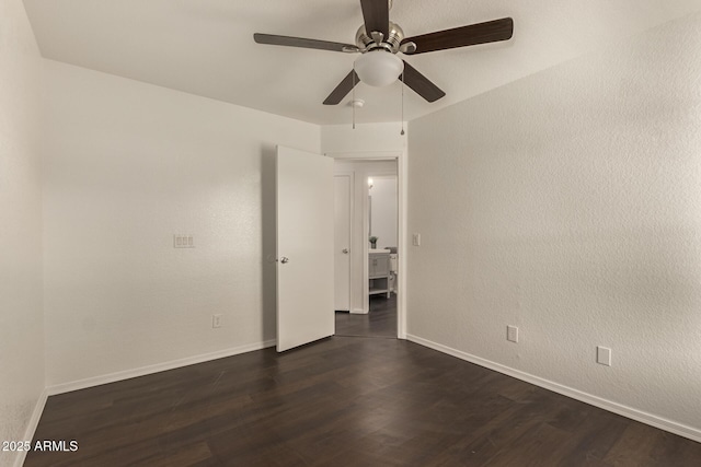 spare room with dark wood finished floors, baseboards, and a ceiling fan