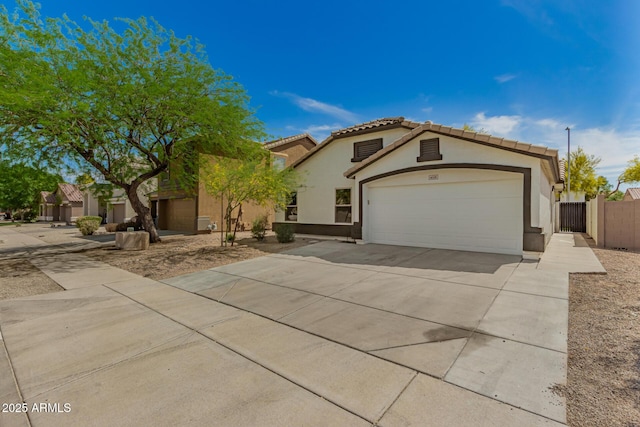 mediterranean / spanish home featuring stucco siding, driveway, a garage, a tiled roof, and fence