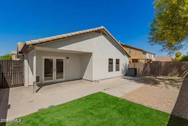 rear view of house featuring stucco siding, fence private yard, a patio, a tile roof, and french doors