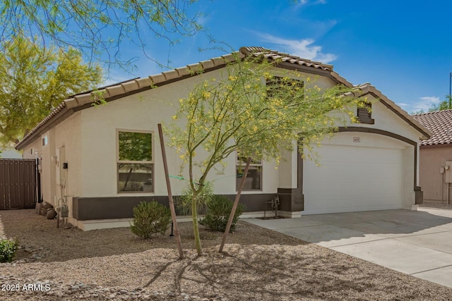 mediterranean / spanish home with concrete driveway, stucco siding, a tiled roof, and an attached garage