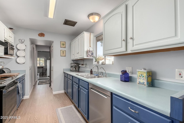 kitchen featuring light hardwood / wood-style floors, white cabinetry, blue cabinets, appliances with stainless steel finishes, and sink