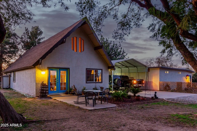 back house at dusk featuring french doors and a carport