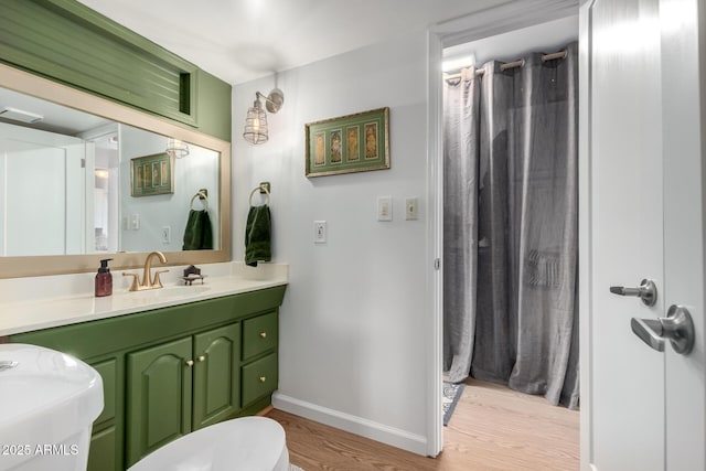 bathroom with toilet, hardwood / wood-style flooring, and vanity