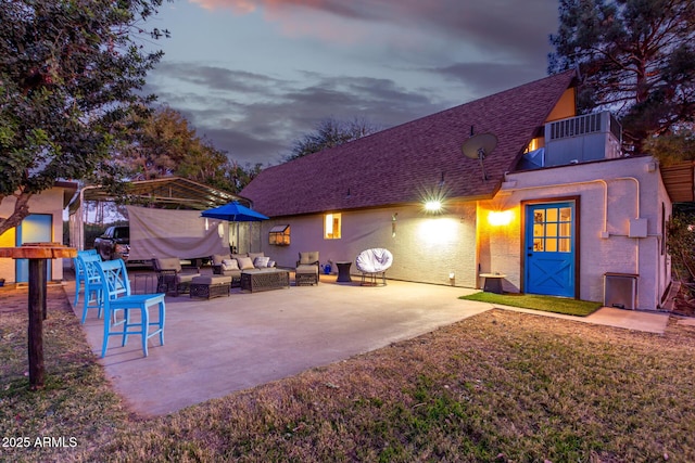 back house at dusk with central air condition unit, a patio area, and an outdoor living space