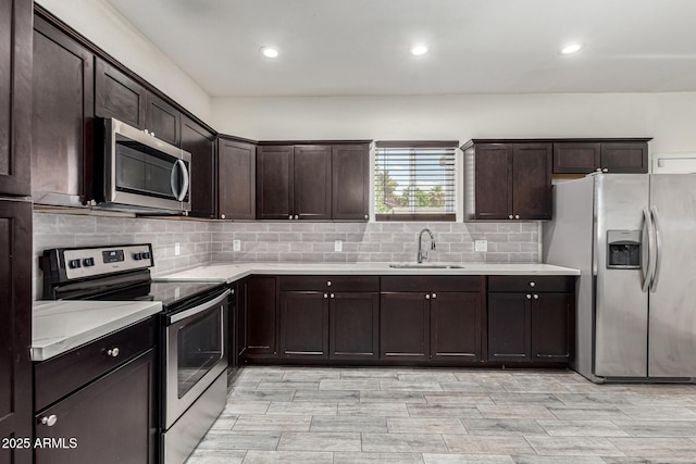 kitchen with dark brown cabinets, appliances with stainless steel finishes, light countertops, and a sink