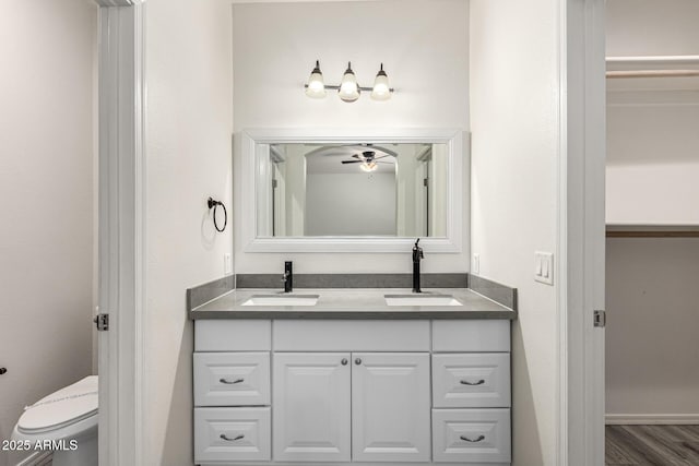 full bath with ceiling fan, double vanity, toilet, and a sink