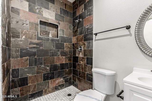 bathroom with vanity, toilet, and tiled shower