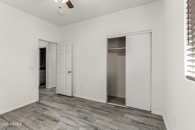 unfurnished bedroom with a closet, baseboards, wood finished floors, and a ceiling fan