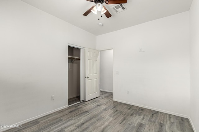 unfurnished bedroom featuring visible vents, baseboards, wood finished floors, a closet, and a ceiling fan